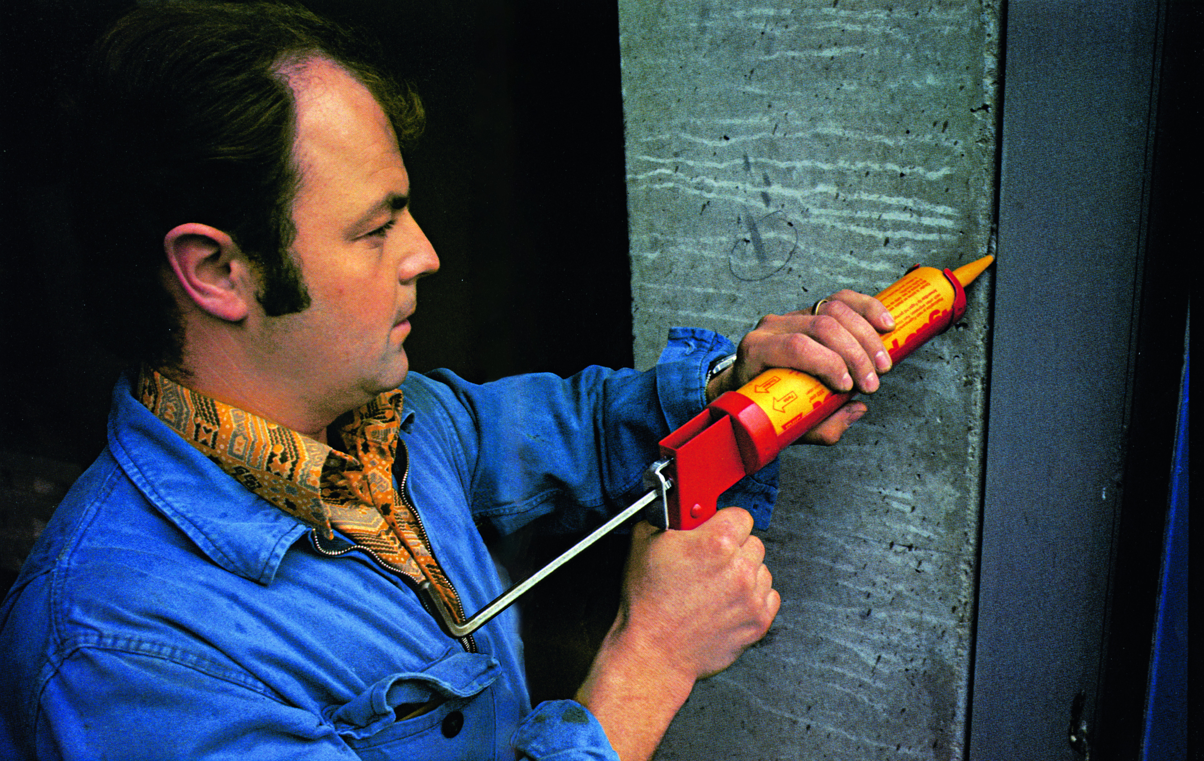 Worker man applying Sikaflex® joint sealant at concrete building joint